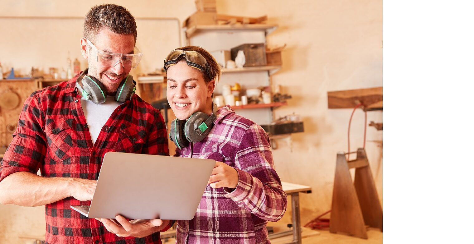 Junge Handwerker schauen zusammen auf einen Laptop 