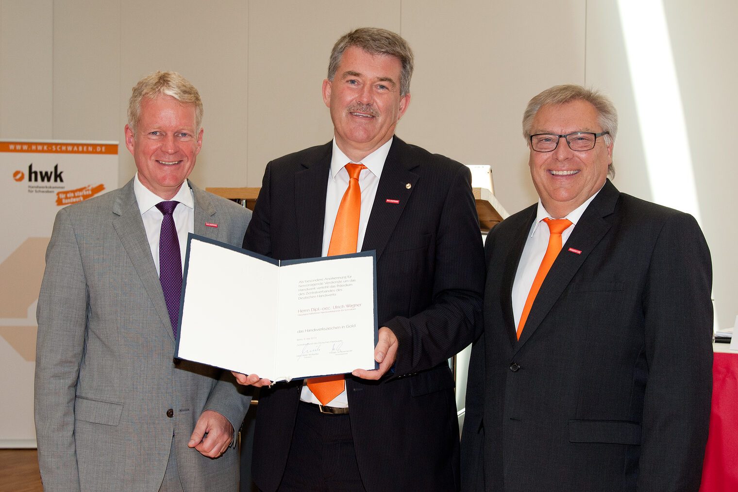 Holger Schwannecke, Generalsekretär des Zentralverbandes des Deutschen Handwerks (ZDH) überreicht das Handwerkszeichen in Gold. Rechts im Bild Hans-Peter Rauch, Präsident der HWK Schwaben